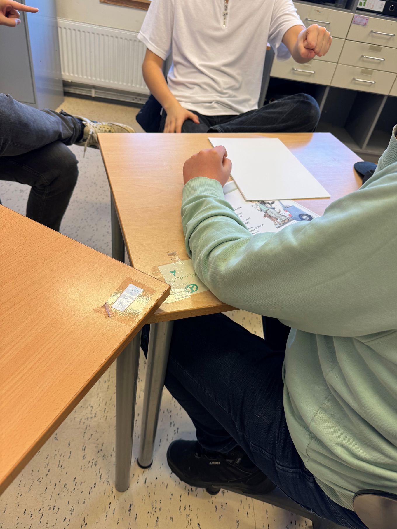 En gruppe elever som sitter på stoler ved et bord med papirer og drøfter