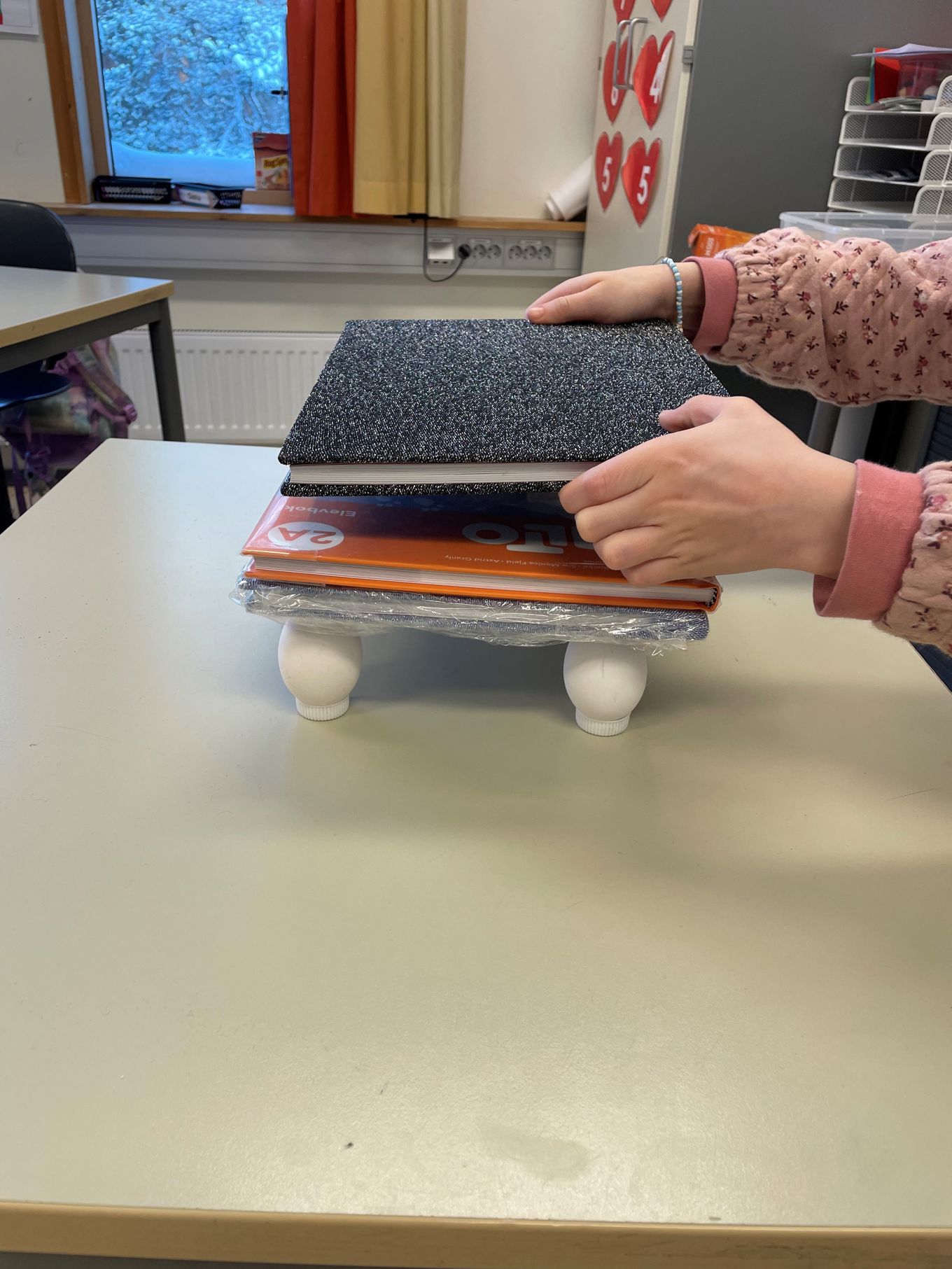 en person plasserer bøker oppå flasker