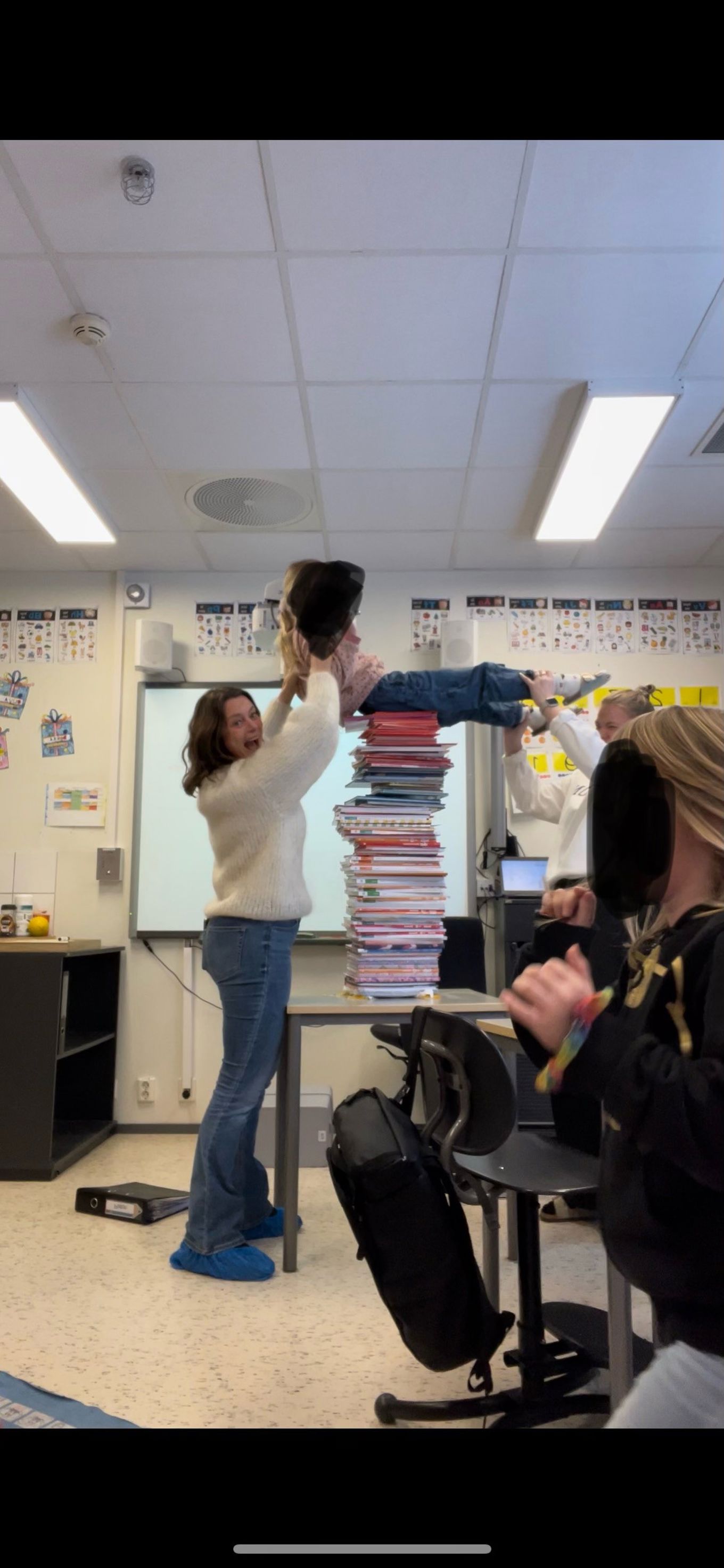 To lærere legger et barn oppå stabelen med bøker